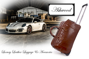 A large, chestnut coloured leather wheeled holdall next to a white sports car with the text reading 'lucury leather luggage and accessories' and 'Ashwood'.