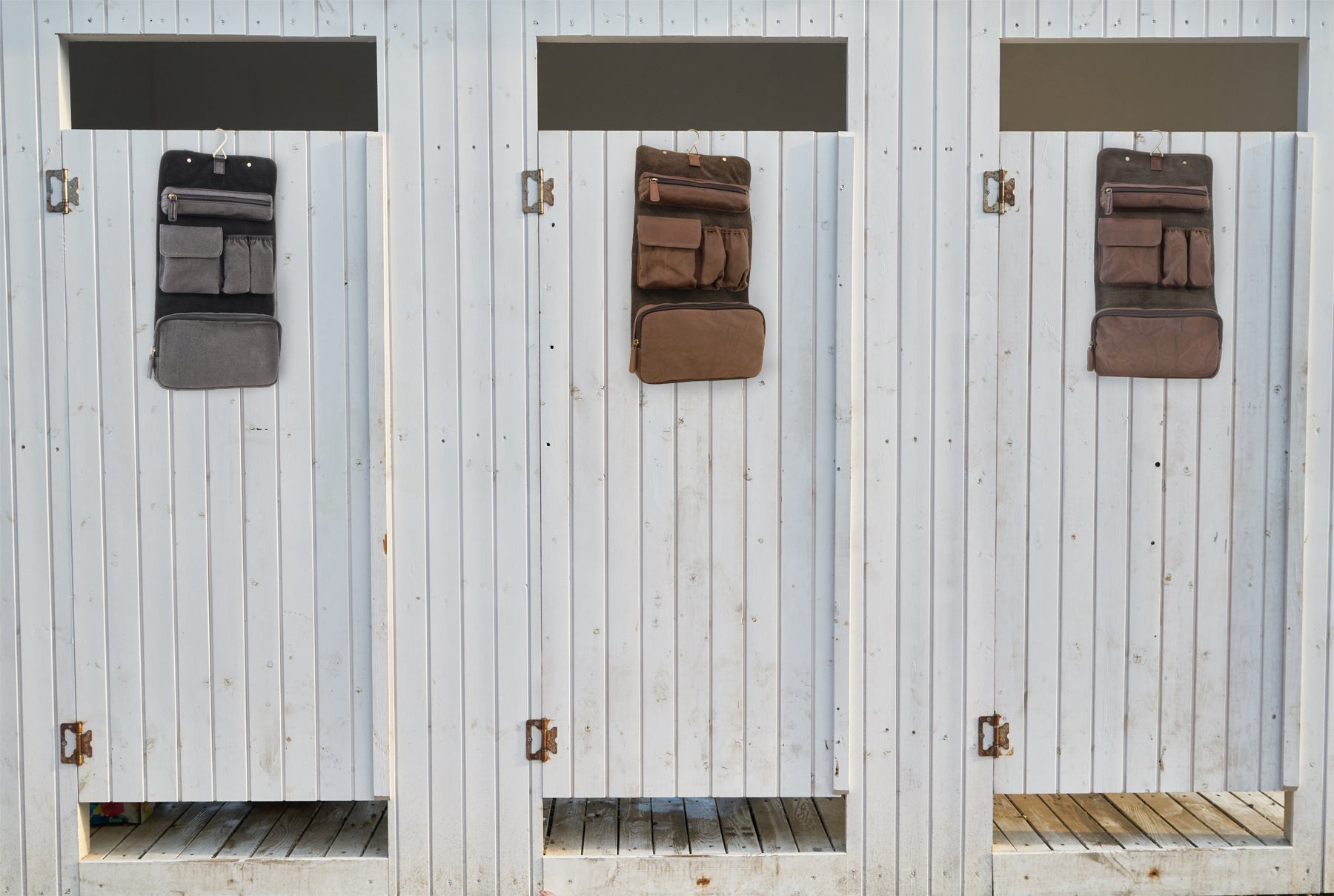 Collection of different coloured wash bags hanging on the back of shower room doors.