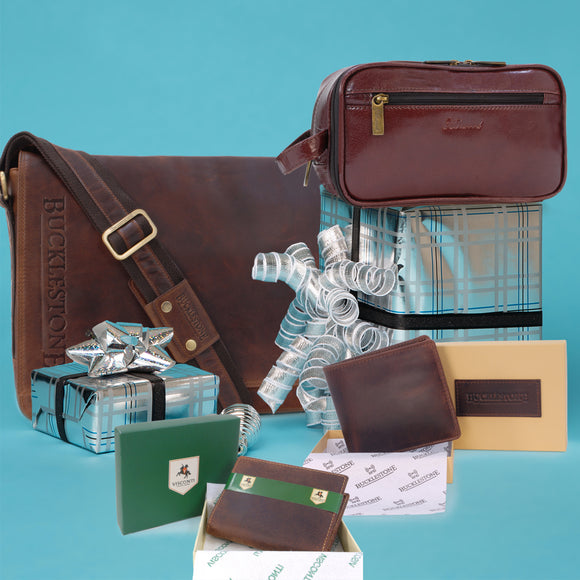 Collection of leather messenger bags, wash bags and wallets sat on top of wrapped gifts for men.